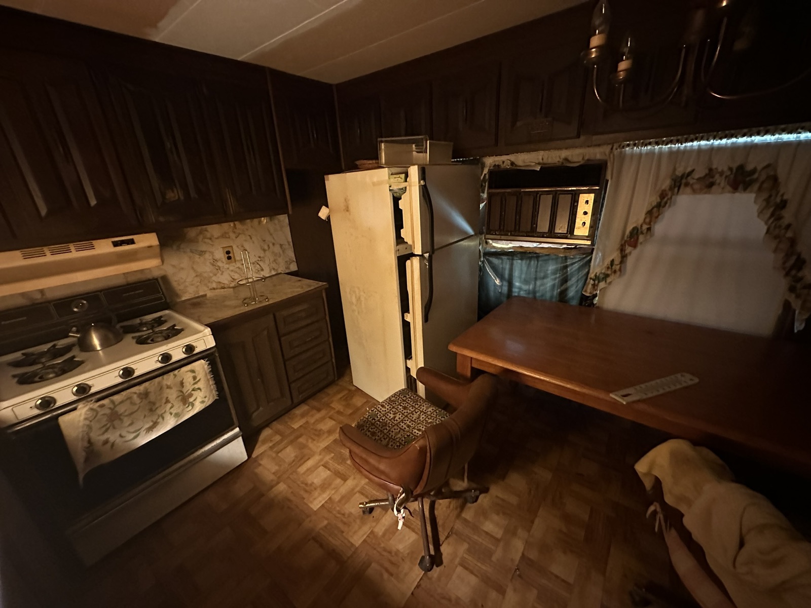 Dark, dated kitchen before renovation with brown raised-panel cabinets and a closed-off layout