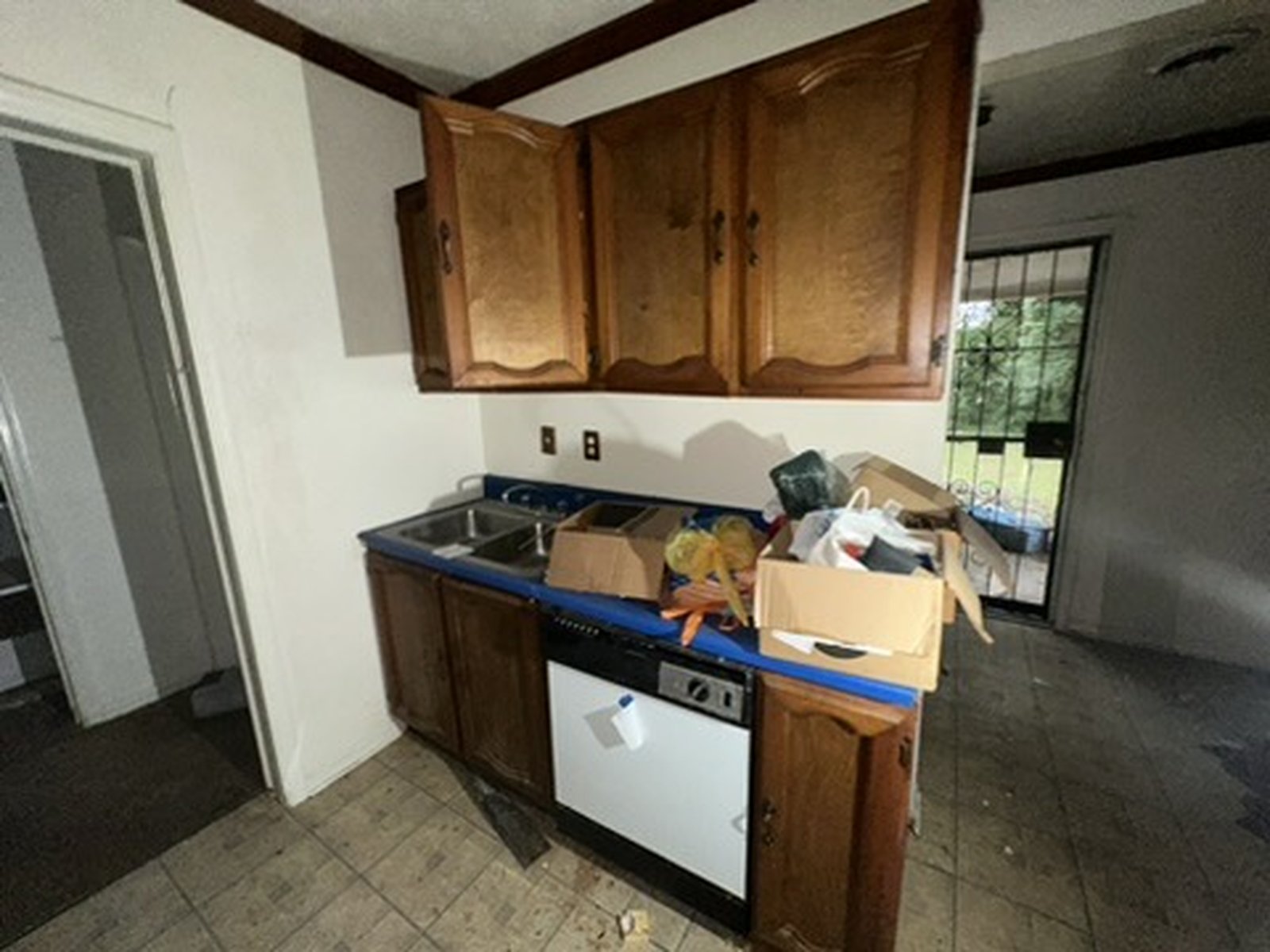 Dark, cluttered kitchen before renovation with worn brown cabinets and dated finishes