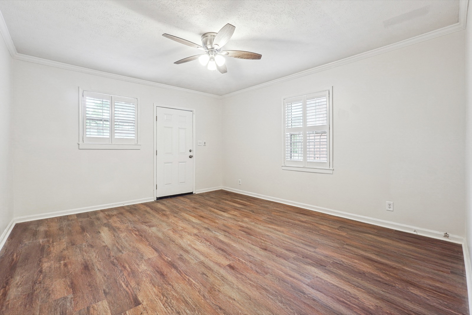 Bright renovated living room with new luxury vinyl plank floors, fresh white paint, and plantation shutters