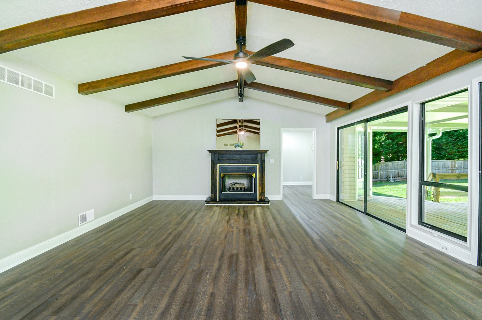 Bright renovated great room with refinished wood beams, fireplace, and natural light